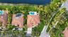 Aerial view of a waterfront property featuring a multi-hipped tile roof, a private swimming pool with a concrete patio, and mature landscaping