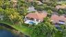 Aerial perspective of a single-story residence featuring a tile roof, a rear patio with an inset swimming pool and spa, and expansive lawn space with 