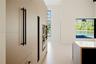 Full-height, flat-panel cabinetry featuring matte black hardware, integrated double wall ovens, expansive floor-to-ceiling windows, and a waterfall-ed