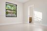 Neutral-toned interior space featuring a large window with black framing and light-colored flooring