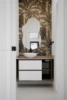 Floating vanity with a white vessel sink, matte black wall-mounted faucet, organic-shaped mirror, and patterned wall covering