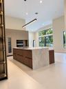 Kitchen featuring a central island with a stone-finish waterfall countertop, built-in dual wall ovens, integrated wine refrigeration, linear pendant l