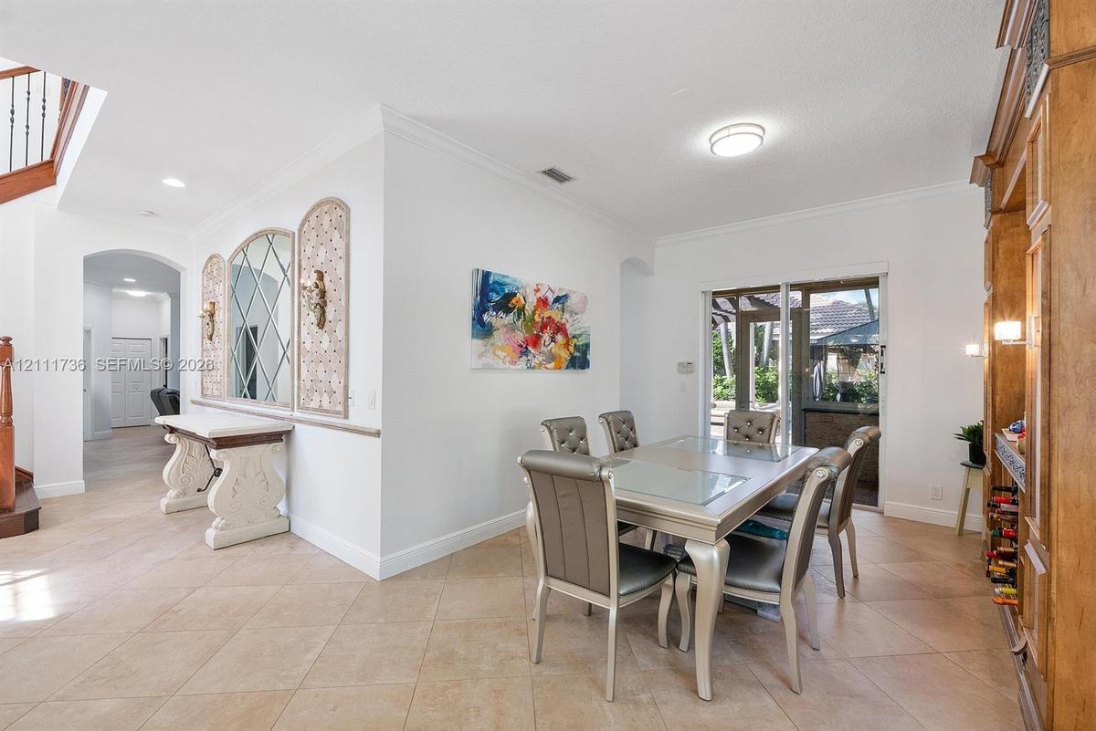 Dining area featuring diagonal tile flooring, built-in floor-to-ceiling wood cabinetry, decorative wall mirror with geometric inlay, and sliding glass