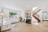 Open-concept area featuring ceramic tile flooring, recessed lighting, ornate wrought iron wall detailing, and a wood staircase with decorative baluste