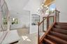 Grand foyer featuring a high ceiling, wood-finish staircase with decorative metal balusters, arched window, wrought-iron wall accent, and multi-arm ch