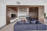 Floor-to-ceiling sliding glass doors opening to a balcony, wood-panel wall accents, recessed linear lighting, and modern pendant fixture
