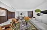 Kitchen featuring wood-finish cabinetry, stone-patterned backsplash, light-colored countertops, integrated cooktop and oven, and upper glass-front cab