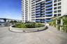 High-rise exterior terrace featuring stone paver flooring, a circular concrete planter with integrated low-voltage lighting, and a white pergola struc