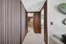 Bathroom featuring floor-to-ceiling textured stone wall tiles, wood-finish vanity with a stone countertop, integrated sink, and glass-enclosed shower 