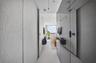 Walk-in shower with frameless glass enclosure, matte black fixtures, integrated wall shelving, floor-to-ceiling stone tile, and vertical wood-finish p