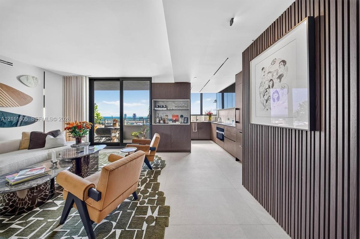 Kitchen featuring flat-panel wood-finish cabinetry, integrated appliances, stone backsplash, built-in dry bar, and large-format tile flooring