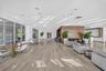 Dark wood-finish cabinetry, built-in wet bar, stone-surface counters, light wood-finish flooring, and minimalist linear recessed lighting