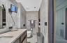 Expansive terrace featuring stone paving, integrated concrete planters, lush landscaping, and low-voltage path lighting