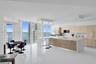 Modern kitchen featuring flat-panel cabinetry, a central island with a stone-finish waterfall countertop, polished tile flooring, and floor-to-ceiling