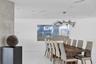 Contemporary living area featuring large-format white tile flooring, a textured concrete-finish accent wall, and a multi-arm modern pendant light fixt