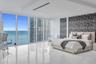 Floor-to-ceiling windows, polished stone-finish flooring, tray ceiling with recessed lighting, and patterned accent wall