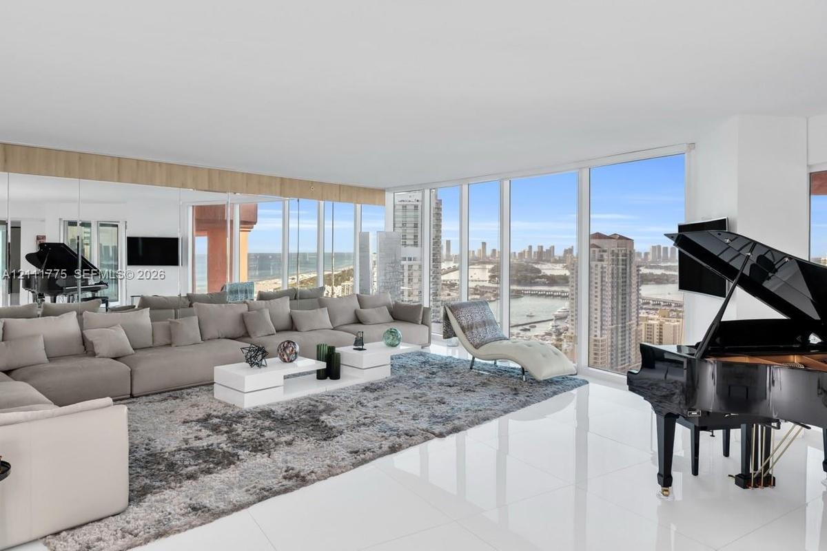 Expansive living area featuring floor-to-ceiling windows, polished large-format tile flooring, built-in mirrored wall panels, and wood-finish ceiling 