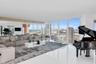 Expansive living area featuring floor-to-ceiling windows, polished large-format tile flooring, built-in mirrored wall panels, and wood-finish ceiling 