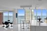 Open-concept kitchen featuring an expansive stone-surface island with integrated seating, floor-to-ceiling glass windows, recessed ceiling lighting, a