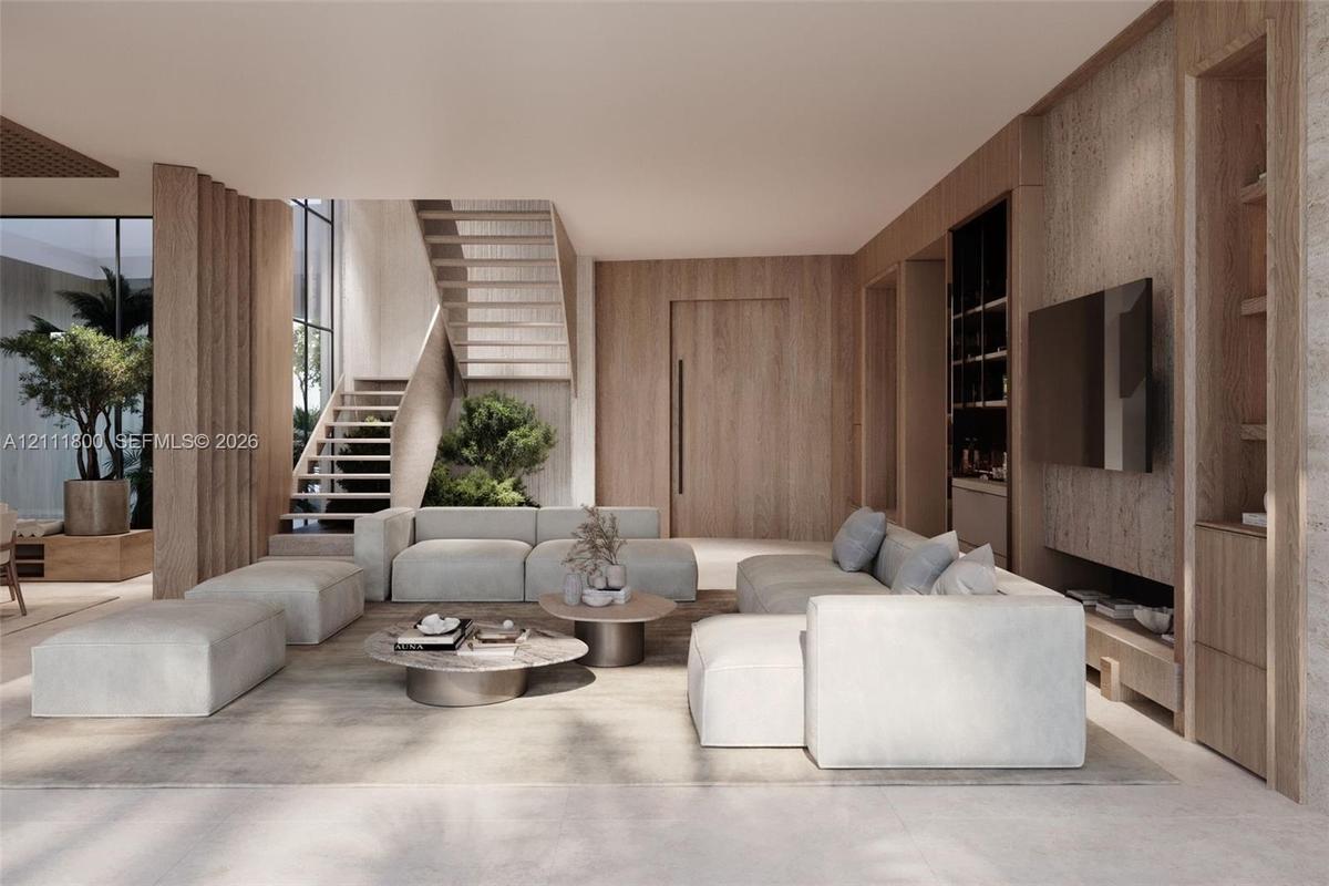 Open-concept living space featuring wood-paneled walls, floor-to-ceiling custom built-in cabinetry, an open-riser wood staircase, and expansive window