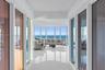 Floor-to-ceiling perimeter windows, polished tile flooring, and expansive water backdrop