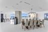 Open-concept interior featuring floor-to-ceiling glass windows, polished tile flooring, stone-clad structural column, and modern multi-bulb ceiling ch