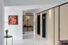 Polished white tile flooring, natural wood-finished wall paneling with black trim, recessed lighting, and integrated elevator access