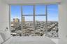 Floor-to-ceiling windows featuring expansive urban panoramas, sleek white walls, and polished flooring