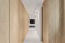 Hallway featuring full-height light wood-finish cabinetry, polished tile flooring, and recessed ceiling lighting