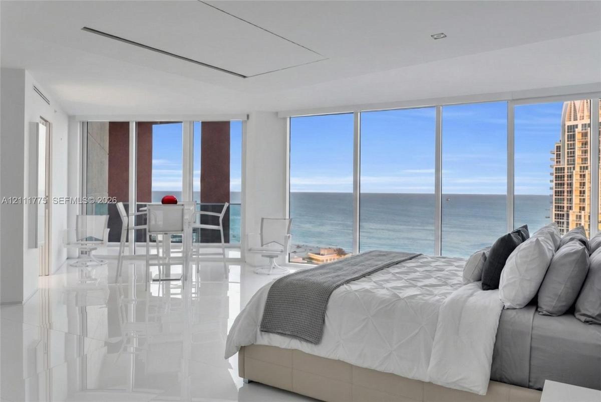 Floor-to-ceiling glass walls, expansive ocean scenery, and white polished flooring