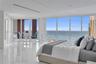 Floor-to-ceiling glass walls, expansive ocean scenery, and white polished flooring