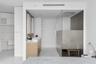 Wood-finish double vanity with rectangular sinks, white countertop, and frameless glass-enclosed shower with large-format tile wall
