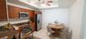 Kitchen featuring wood-finish cabinetry, stone countertops, stainless steel appliances, a tray ceiling, and tile flooring