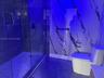 Walk-in shower with floor-to-ceiling tile surround, glass enclosure, integrated wall niche, and rainfall shower head, complemented by a floor-mounted 