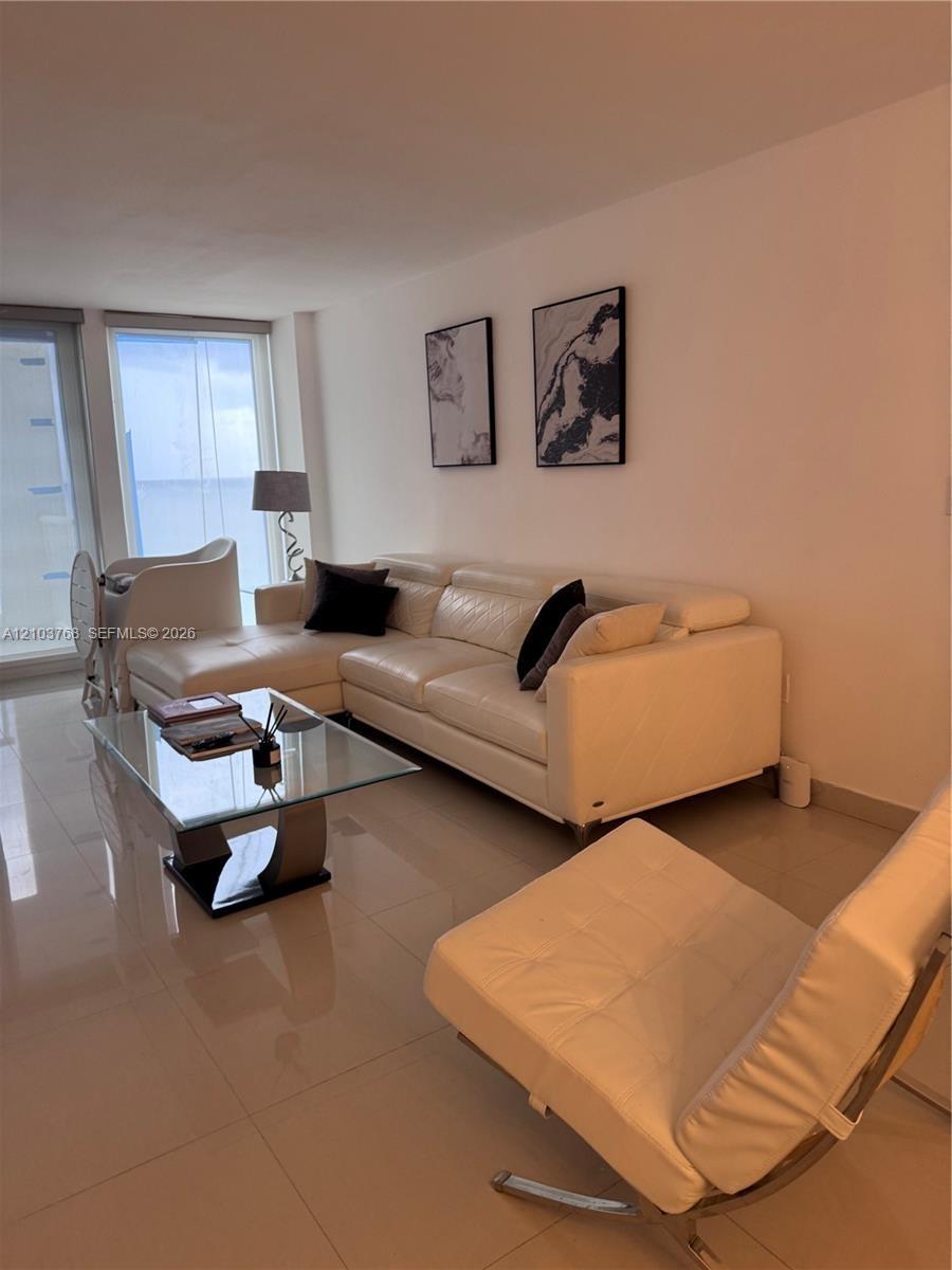 Polished tile flooring, full-height windows, and ocean backdrop