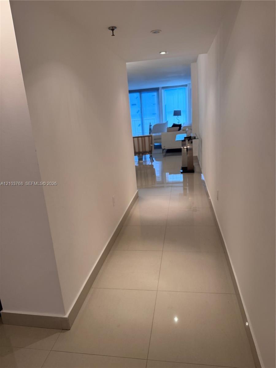 Hallway featuring large-format ceramic tile flooring and recessed ceiling lighting