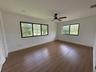 Neutral interior room featuring wood-finish flooring, recessed lighting, a ceiling fan with dark finish blades, and large windows with black frames