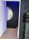 Textured dark charcoal wall paneling with a semicircular backlit mirror, wood-finish flooring, and a decorative glass panel with geometric detailing