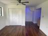 Wood-finish flooring, white paneled bi-fold closet doors, and ceiling-mounted fan with integrated lighting