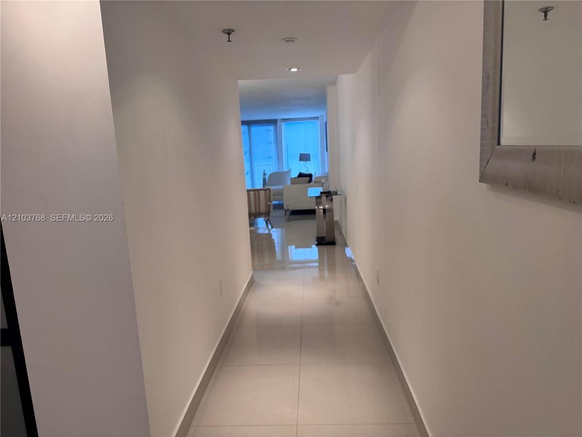 Hallway featuring large-format polished tile flooring and recessed ceiling lighting