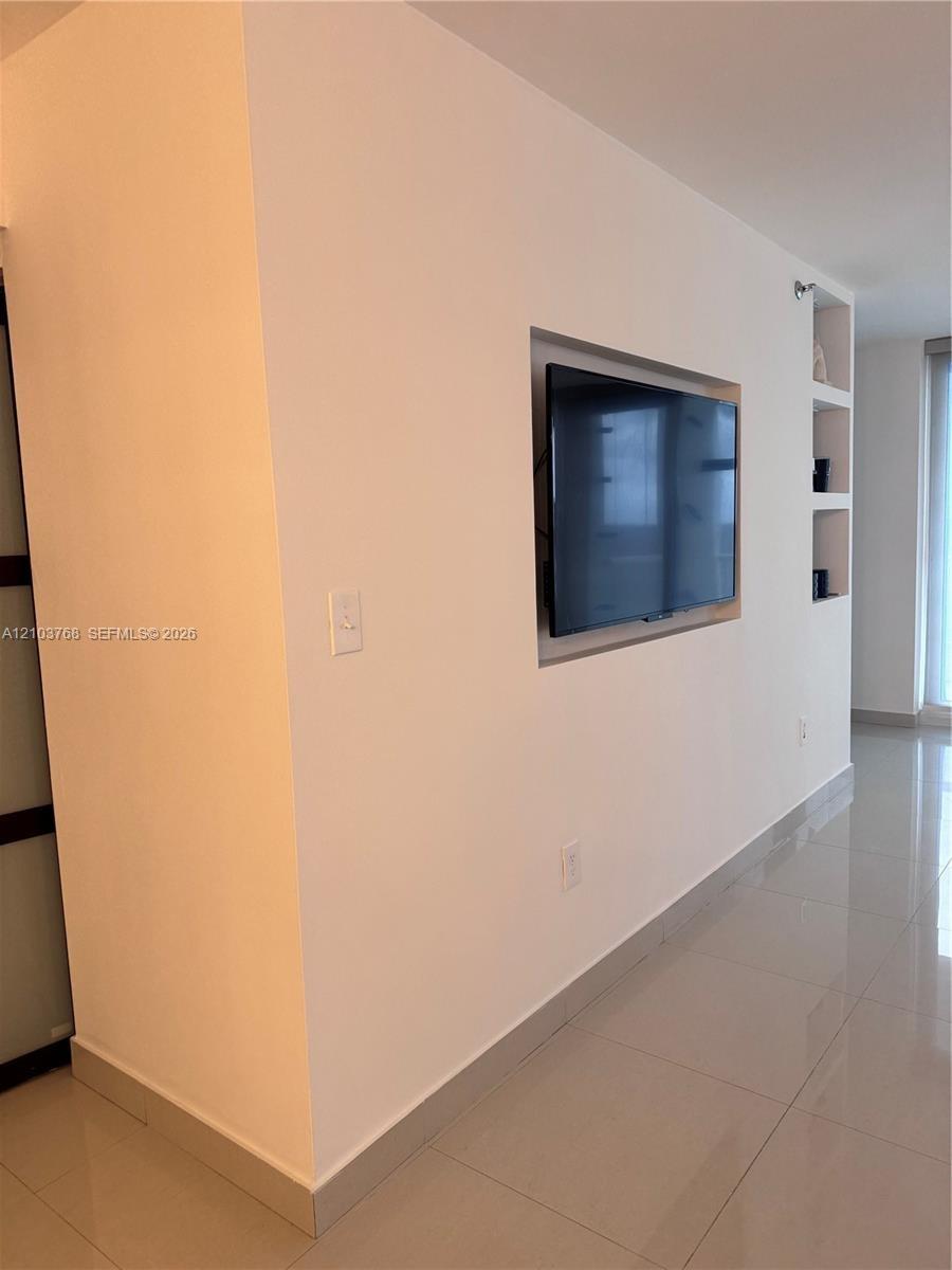 Wall-mounted recessed television niche with integrated shelving and polished tile flooring
