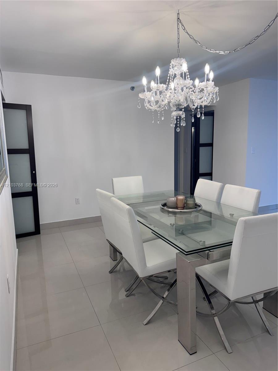 Polished tile flooring, ornate crystal chandelier, and dark-framed doors with frosted glass inserts