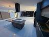 Contemporary kitchen featuring a center island with an integrated cooktop and wood-finish cabinetry, sleek dark countertops, recessed ceiling lighting