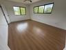 Neutral-toned room featuring wood-finish flooring, dual windows with black frames, and a ceiling-mounted fan
