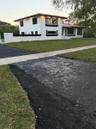 Two-story residence featuring white exterior walls with black trim, a tile roof, an attached privacy wall, and asphalt driveway