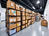 Industrial space featuring an exposed painted ceiling with linear lighting, smooth epoxy flooring, and white masonry walls