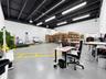 Open-concept industrial space featuring exposed beam ceilings, finished concrete flooring, painted masonry walls, and linear fluorescent lighting