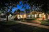 Single-story residence featuring a stucco exterior, multi-pitched roofline, paved driveway, integrated garage, and mature landscaping