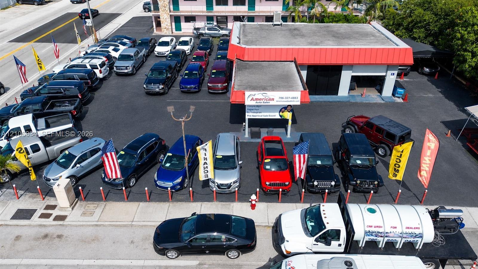 Commercial property featuring an asphalt-paved lot, a flat-roof structure with a covered service bay, and prominent street-level frontage