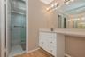 Primary Bathroom vanity featuring a white cabinet base, stone-look countertop, integrated sink, and full-width wall mirror with attached multi-bulb li